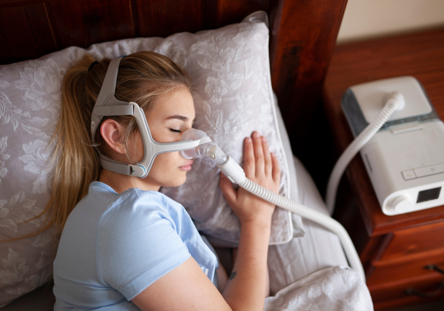 Young female sleeping with CPAP machine for sleep apnea.